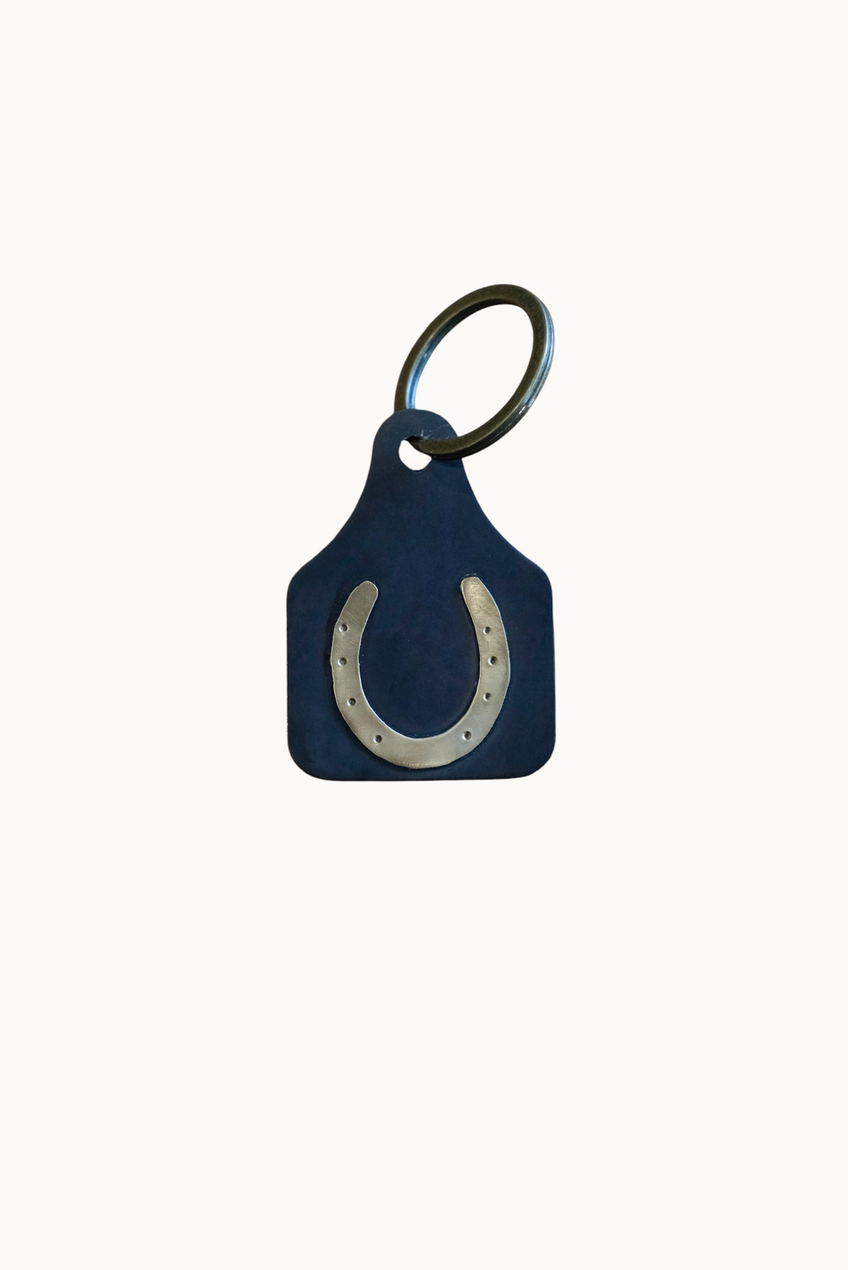 Wilkinson's Fine Goods horseshoe stock tag made from 16-gauge steel with soldered brass on a wooden surface