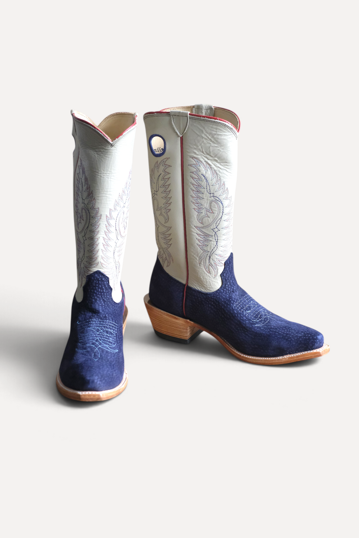 Pair of navy carpincho cowboy boots with cream embroidered tops, front view