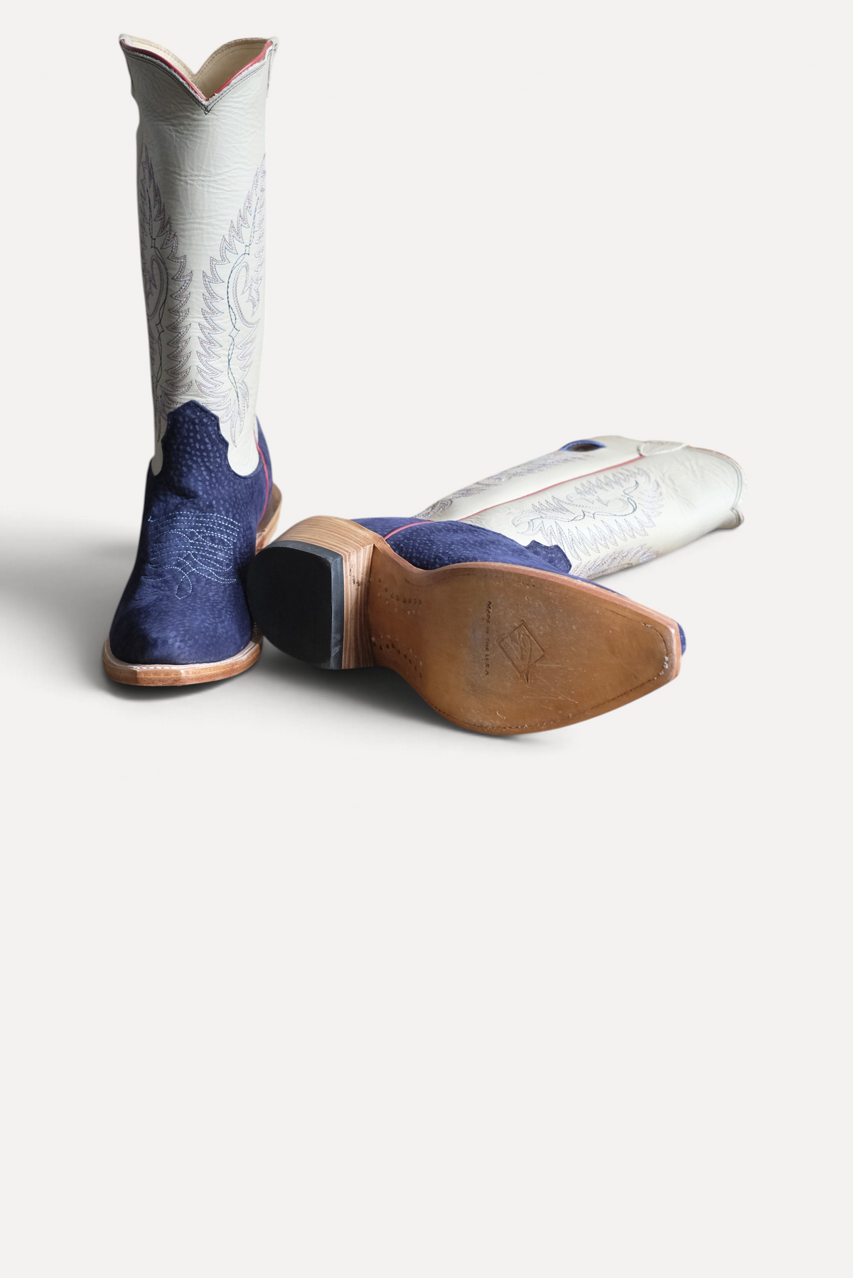 Navy carpincho cowboy boots showing the leather sole and stacked heel