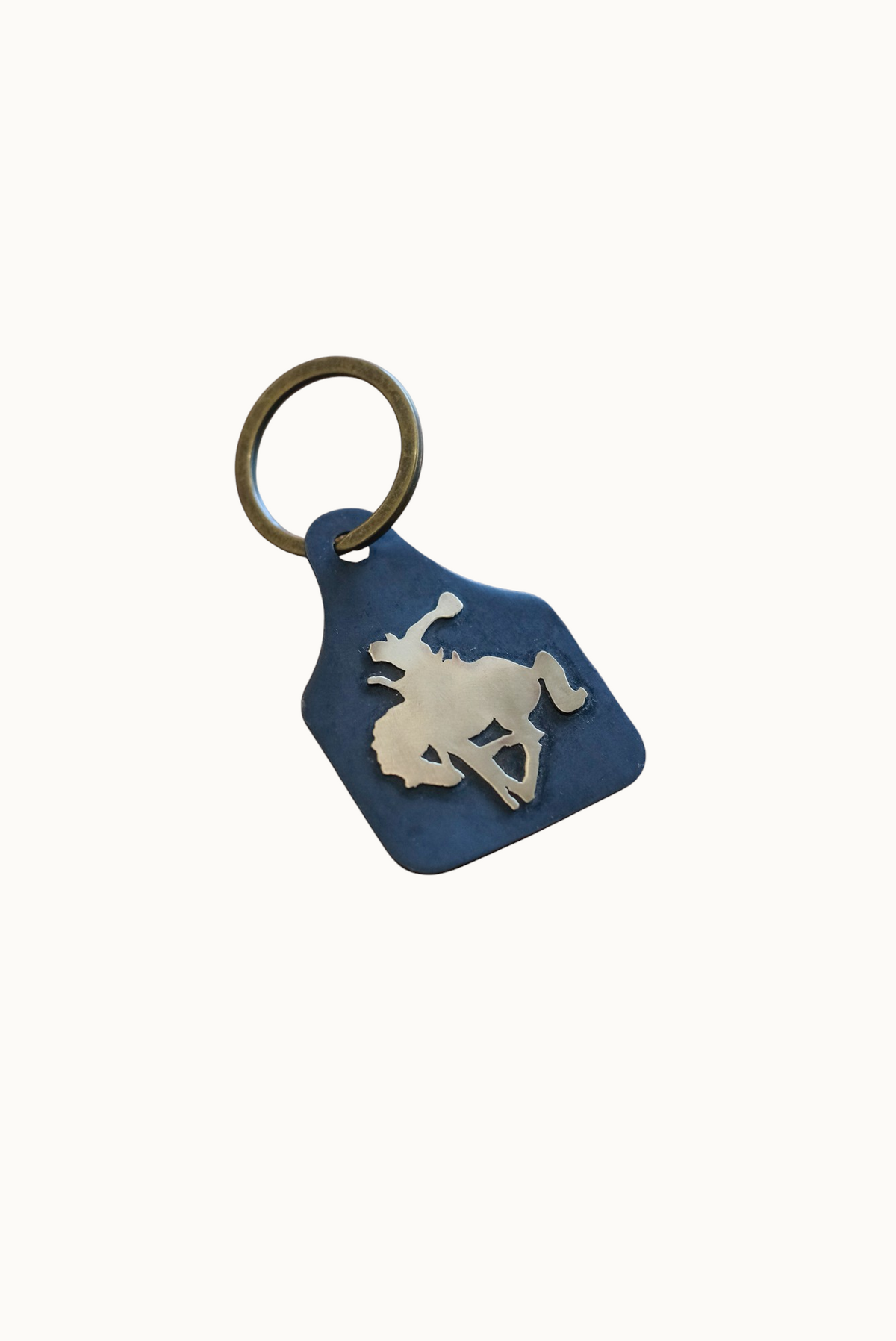 Wilkinson's Fine Goods Bronc Rider stock tag featuring a hand-cut steel cowboy on a bucking horse with brass accents