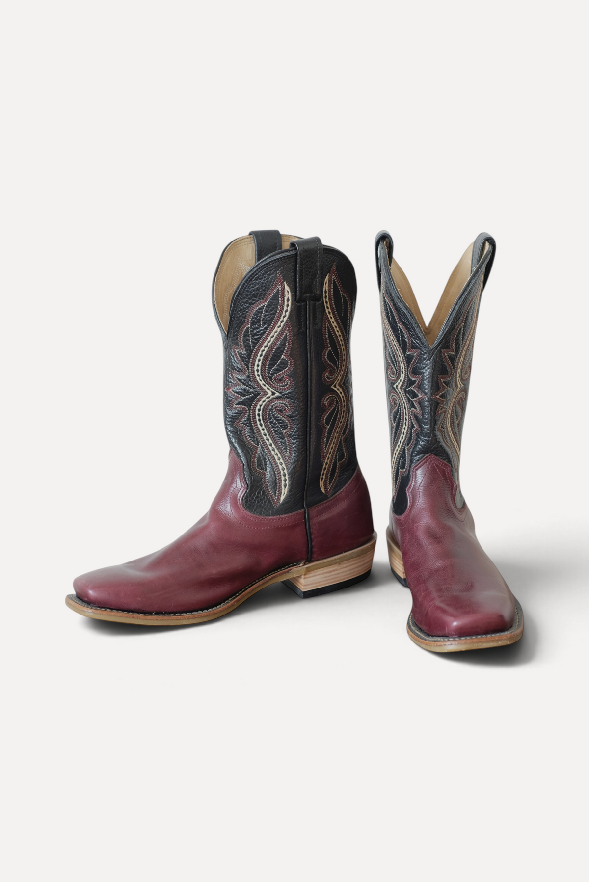Pair of cowboy boots with cabernet leather vamps and black embroidered tops