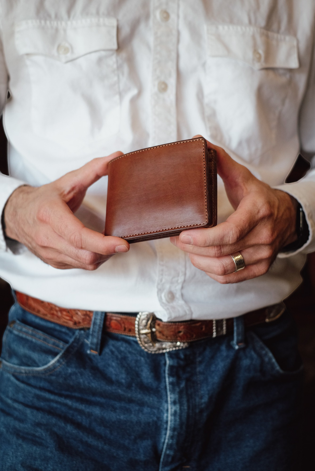 Wilkinson's Fine Goods Classic Billfold in brown Hermann Oak leather held in hands by a man in a white shirt