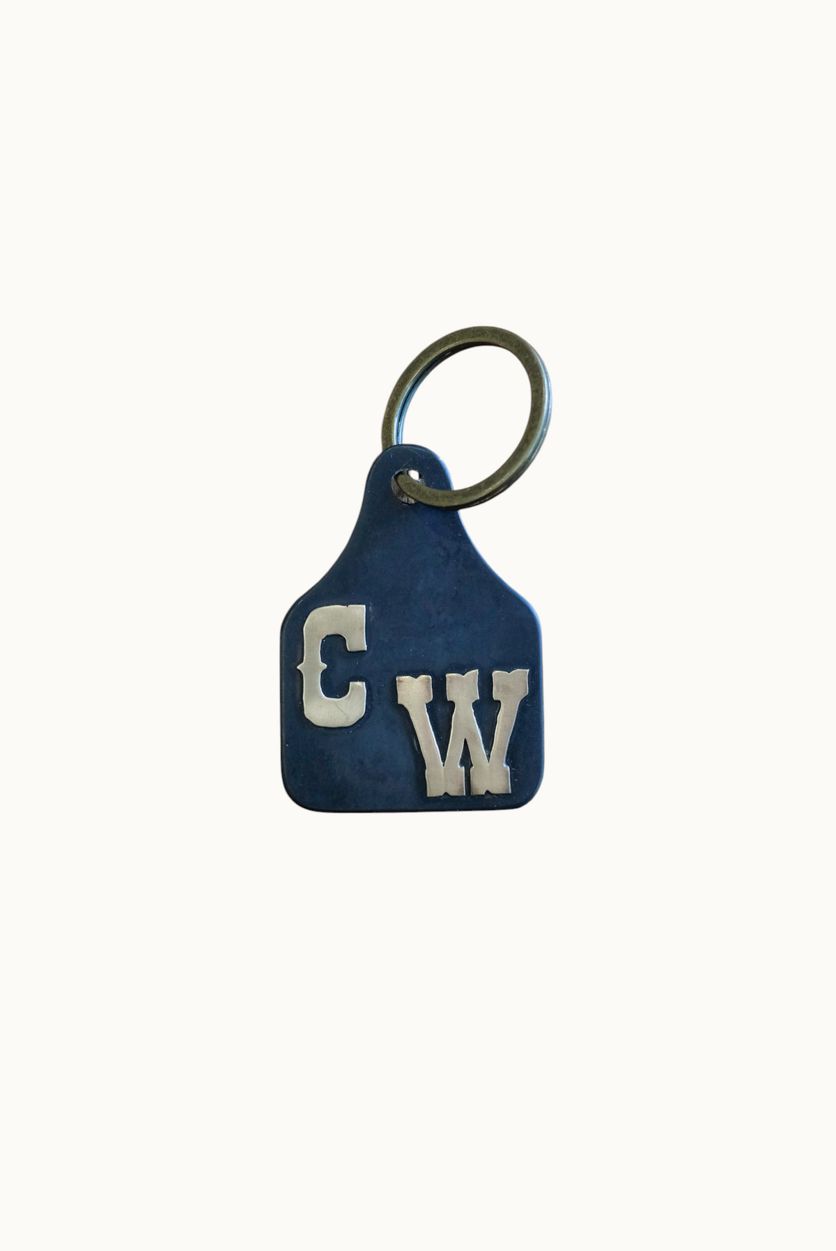 Wilkinson's Fine Goods custom steel stock tag with hand-cut brass initials in western lettering on a keyring.