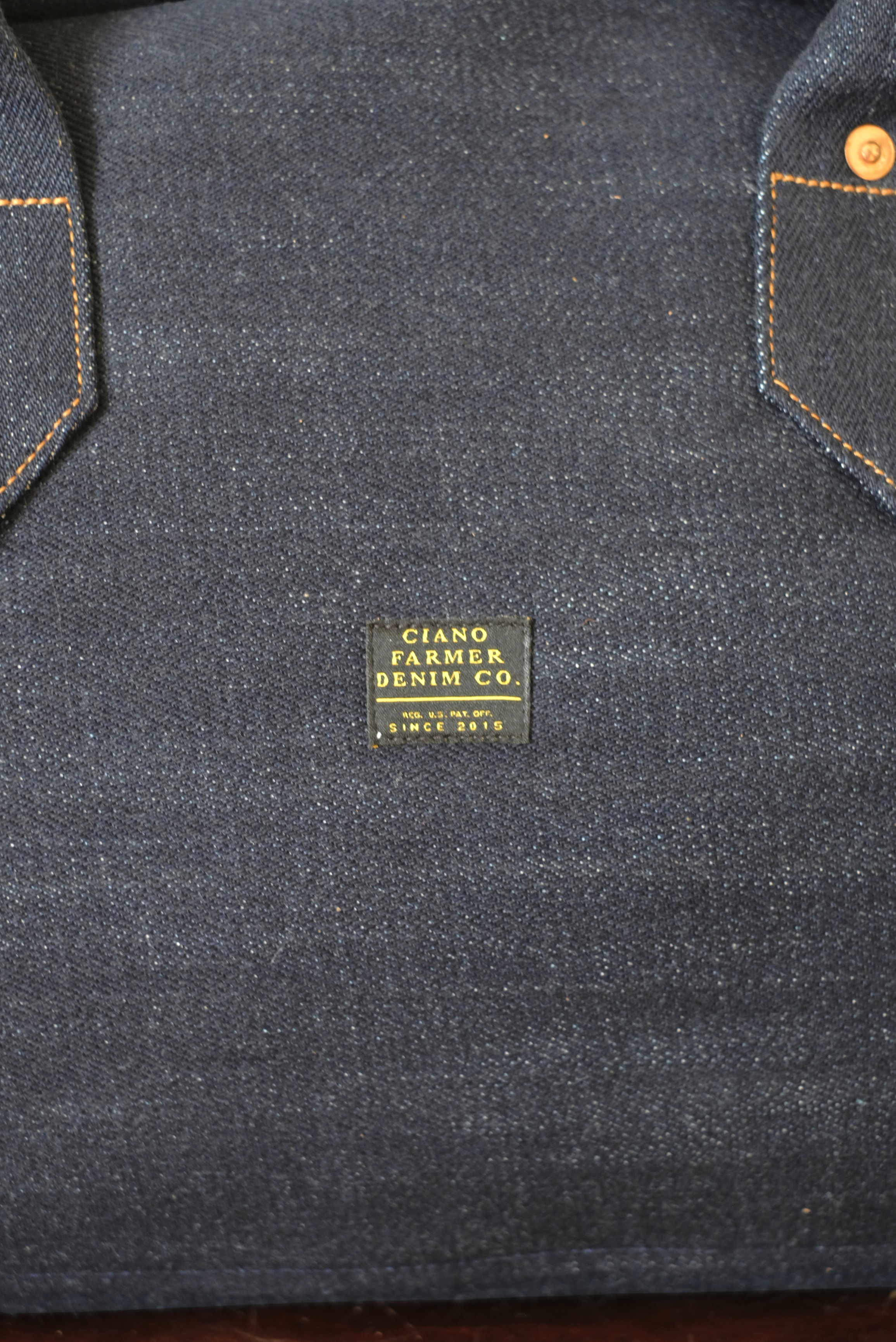 Wilkinson's Fine Goods Ciano Farmer Denim weekender bag featuring rugged dark denim fabric and a branded label.