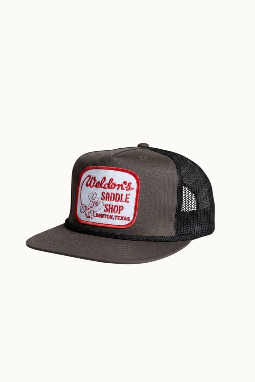 Wilkinson's Fine Goods olive and black trucker hat with vintage Weldon's Saddle Shop patch on the front