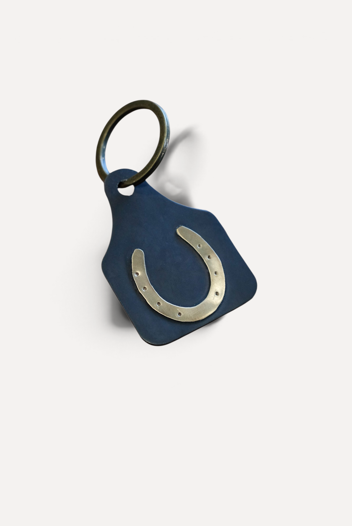 Wilkinson's Fine Goods horseshoe stock tag made of 16-gauge steel with a soldered brass horseshoe on a key ring.