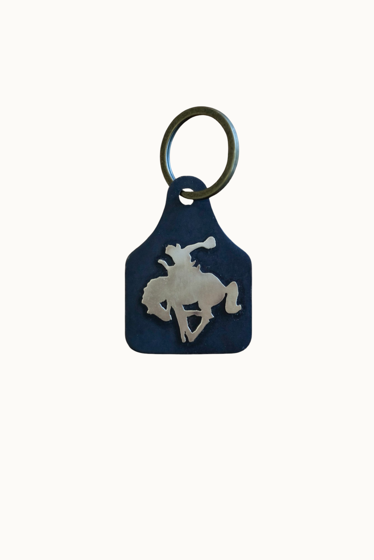 Wilkinson's Fine Goods Bronc Rider stock tag featuring a hand-cut steel silhouette and brass cowboy on a key ring.