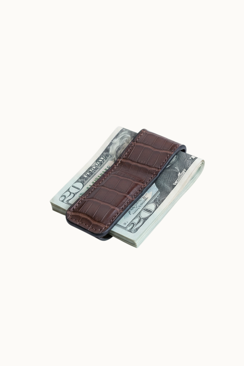 Wilkinson's Fine Goods brown alligator leather money clip with magnetic closure holding a stack of US dollar bills.