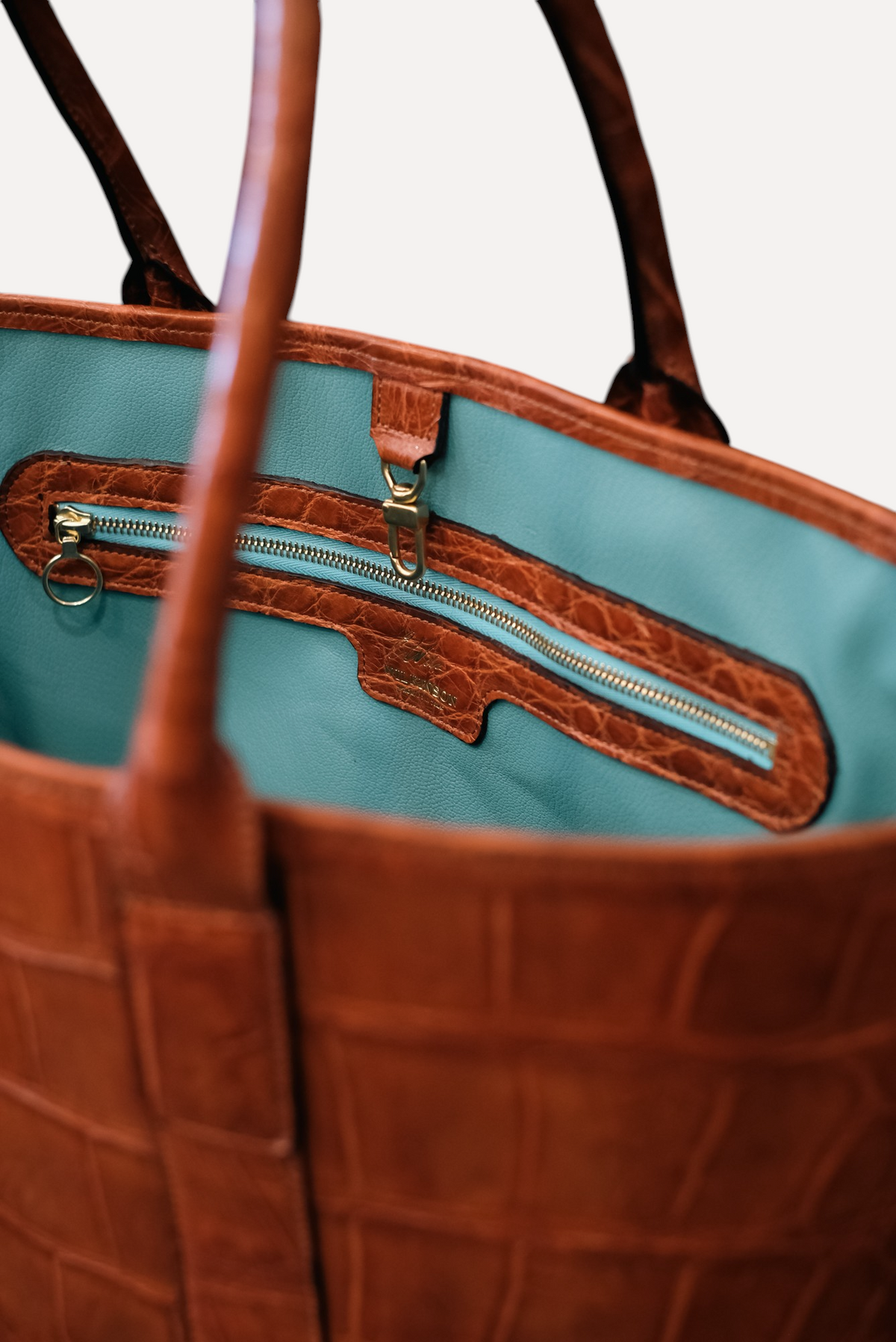 Wilkinson's Fine Goods Legacy Bag in brown American alligator leather with a vibrant turquoise French goat interior.