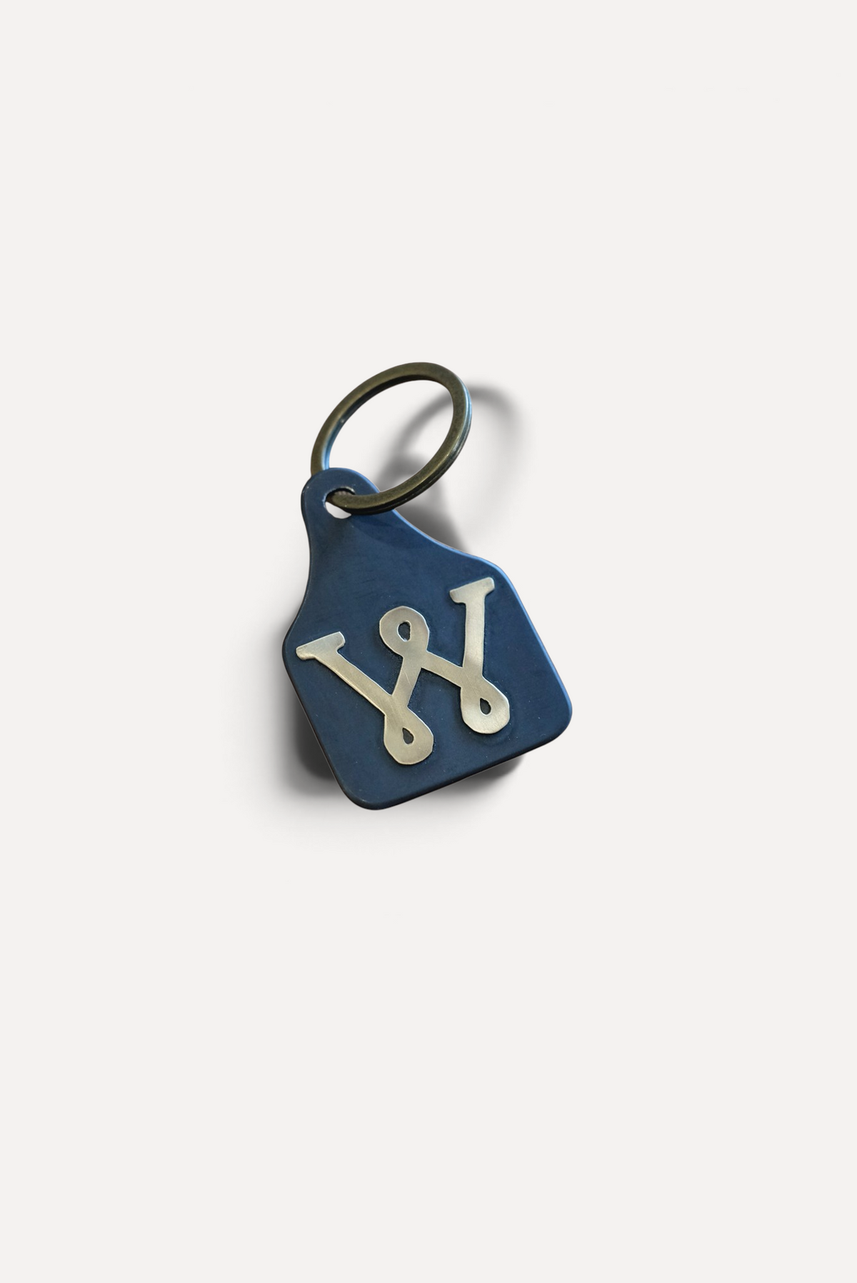 Wilkinson's Fine Goods Loop W stock tag made from hand-cut blue steel with a soldered brass W logo and keyring.