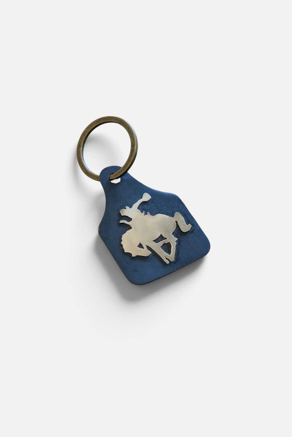 Wilkinson's Fine Goods Bronc Rider stock tag featuring a hand-cut steel cowboy on a bucking horse with brass accents