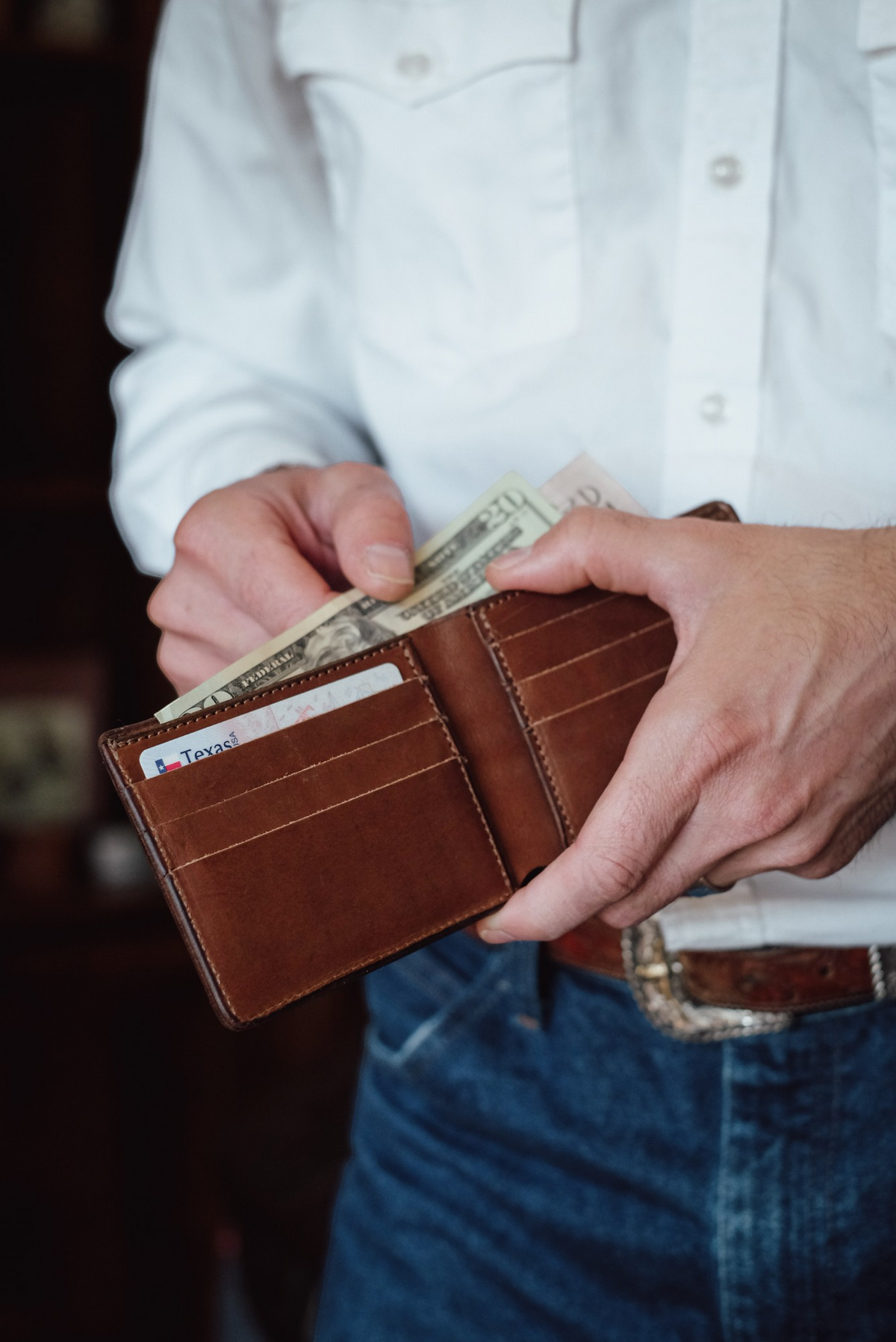 Wilkinson's Fine Goods Classic Billfold in brown Hermann Oak leather with card slots and cash, held by a man.