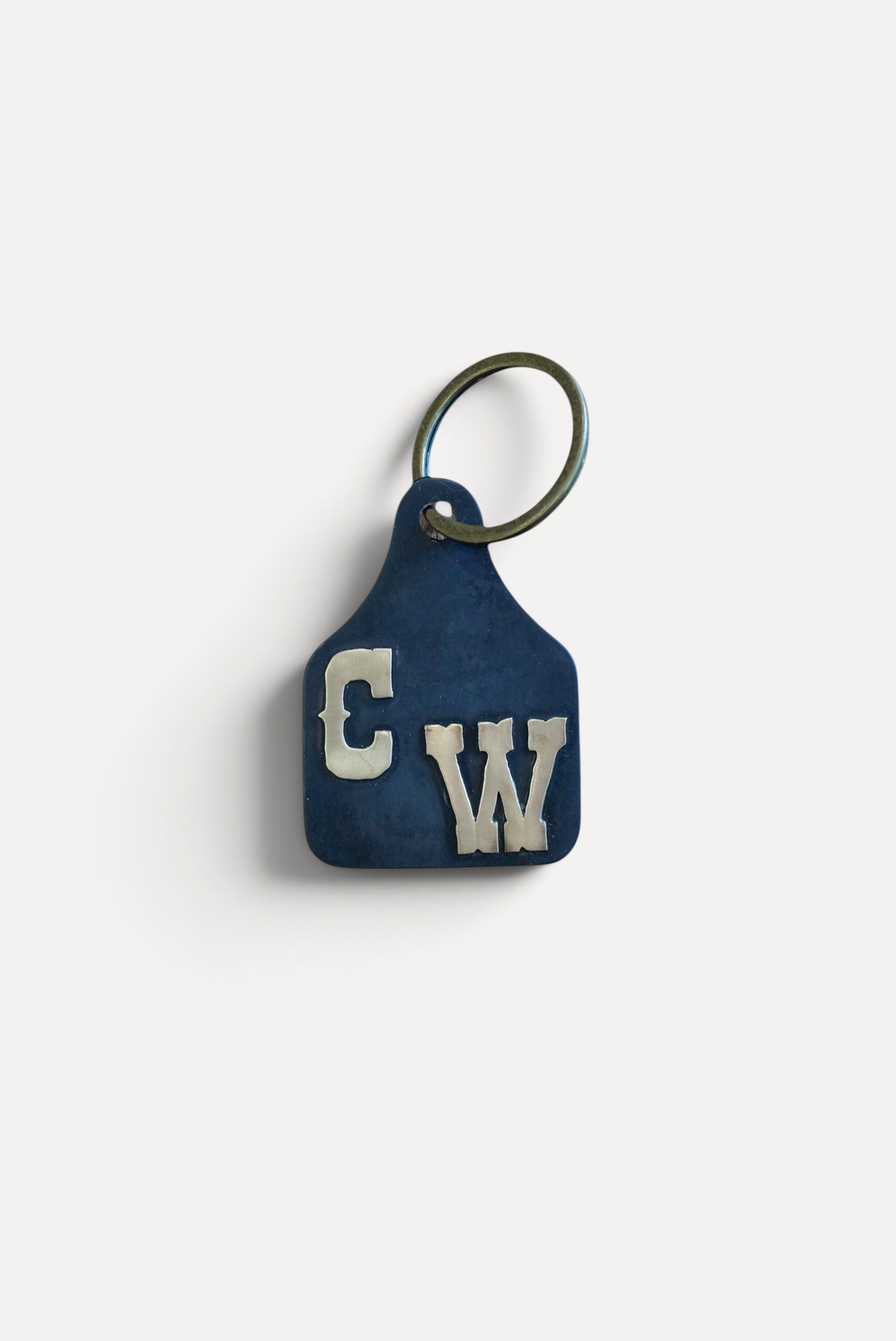 Wilkinson's Fine Goods custom steel stock tag with hand-cut brass initials in western lettering on a keyring.